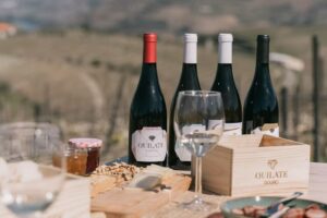 Mesa de prova de vinho numa quinta, copos de vinho do Douro/Porto, ambiente de fim de dia.