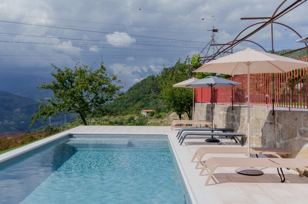 Piscina da Villa Aura com vista sobre a serra e o vale do Douro, portadas vermelhas características.